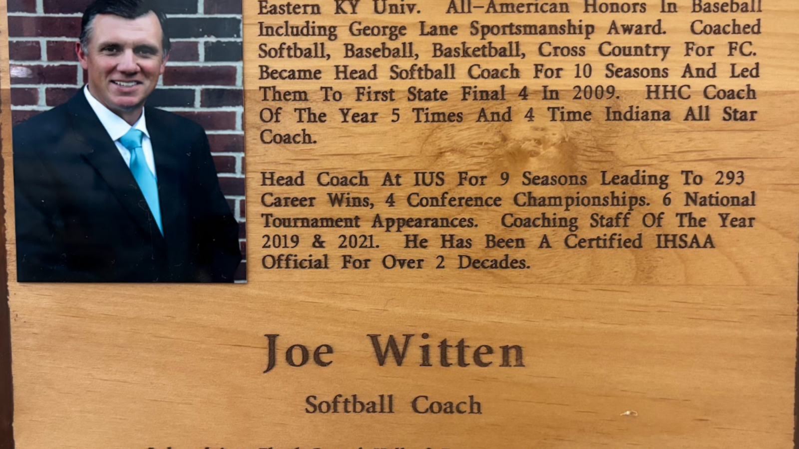 Wood plaque featuring a left-side photo of a man in a suit, with engraved biography text about Joe Witten on the right and notes of his coaching career.