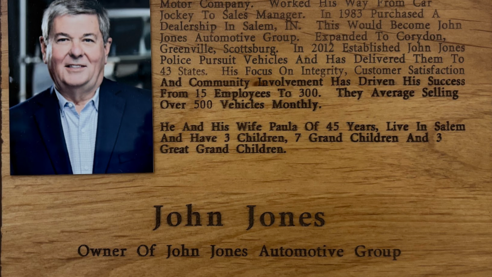 Wooden plaque with a portrait of a man on the left and a long biographical inscription carved on the right side of the wood panel.